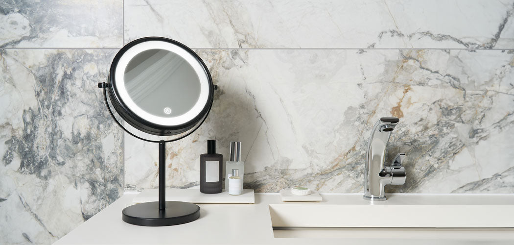 Illuminated black LED bathroom mirror on marble vanity beside luxury toiletries and chrome tap in hotel guest bathroom