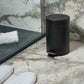 Corby Croft 3 litre black pedal bin placed beside walk-in shower in marble hotel bathroom with slippers and towel