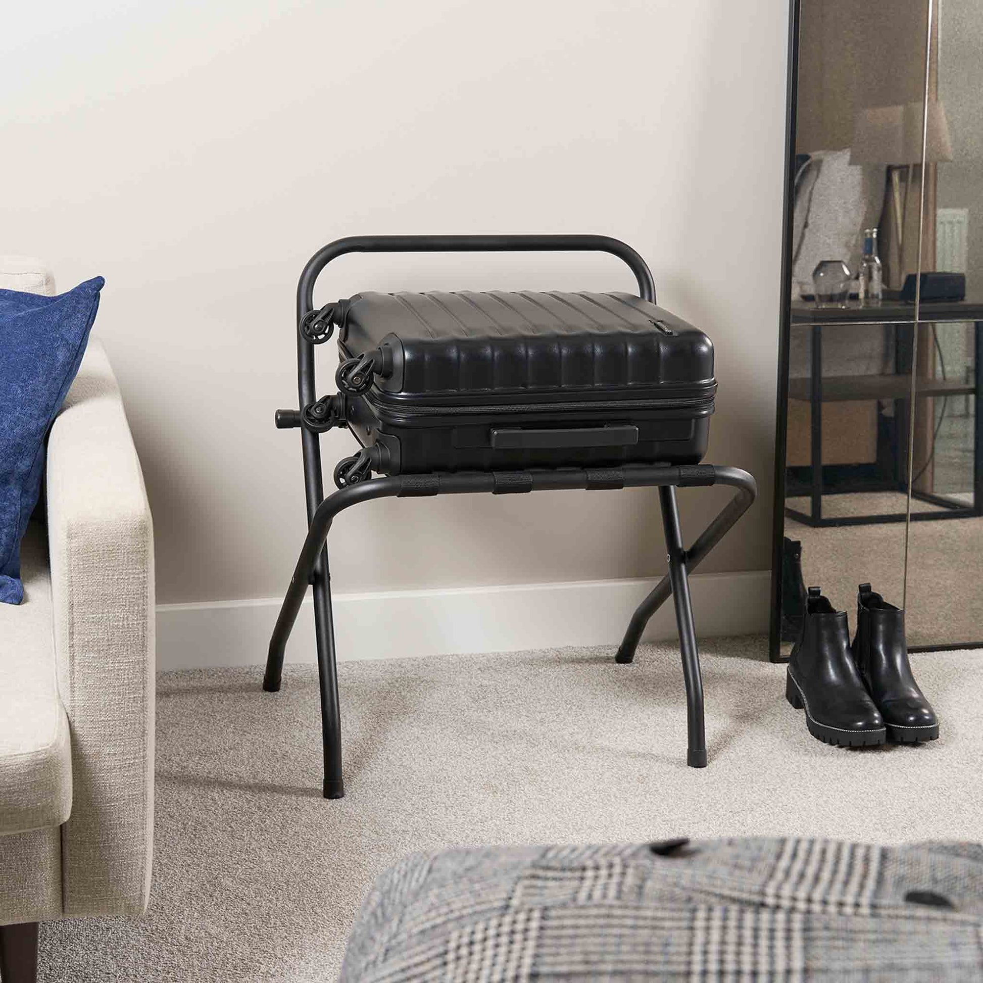 Corby Ashton matte black metal luggage rack with backrest holding suitcase in modern hotel guest room