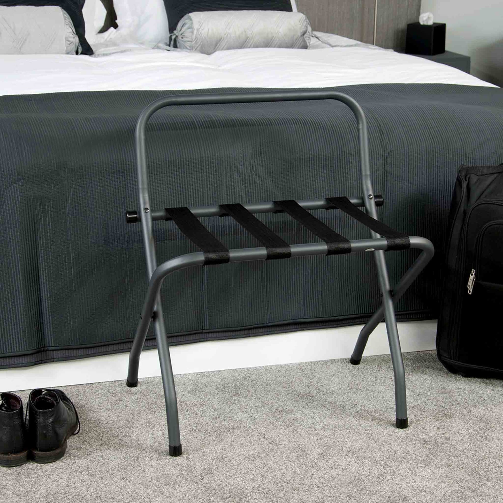 Corby Ashton matte black luggage rack with backrest positioned at foot of hotel bed in modern guest room