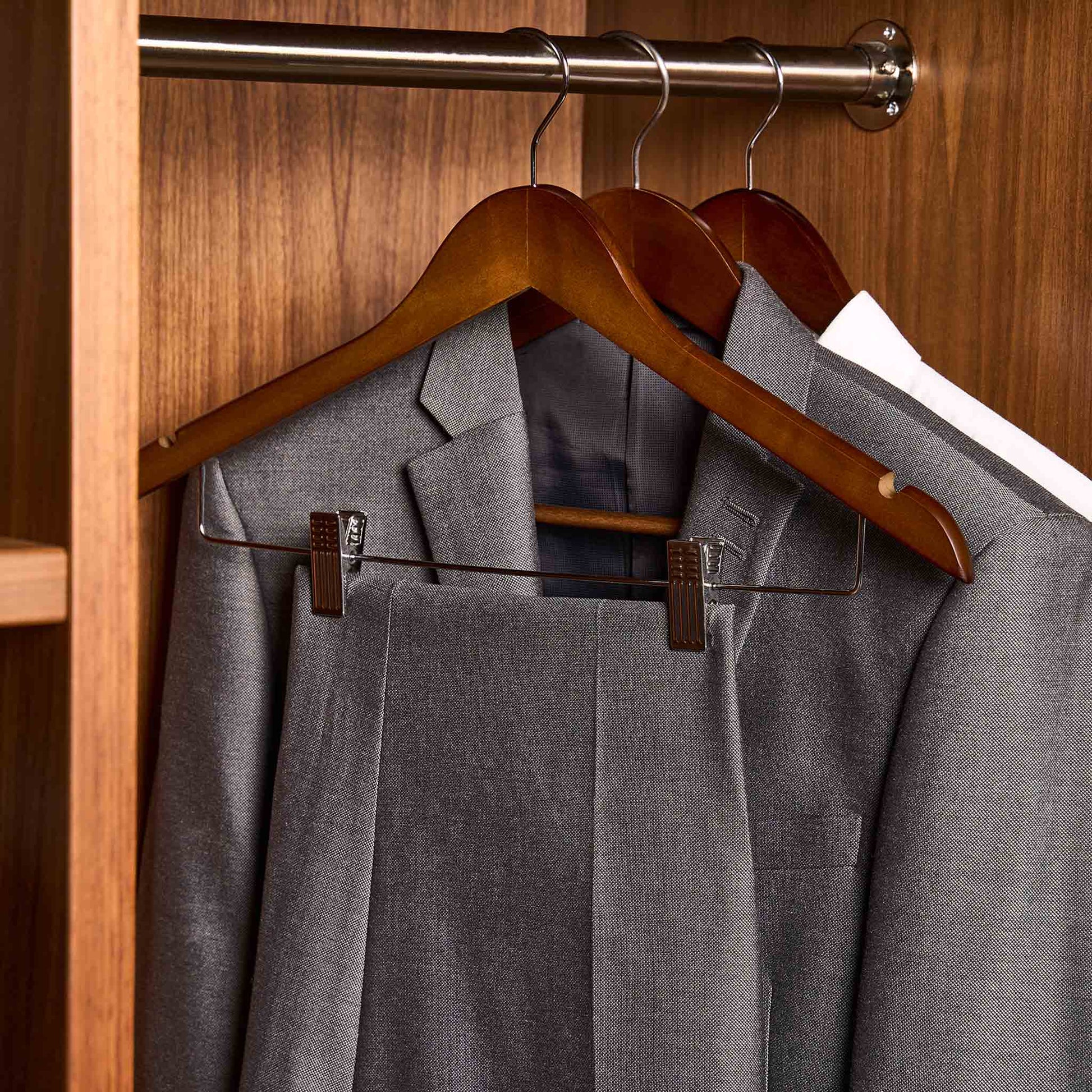 Corby Burlington dark wood skirt hangers with chrome hooks and clips holding suit and trousers in hotel wardrobe