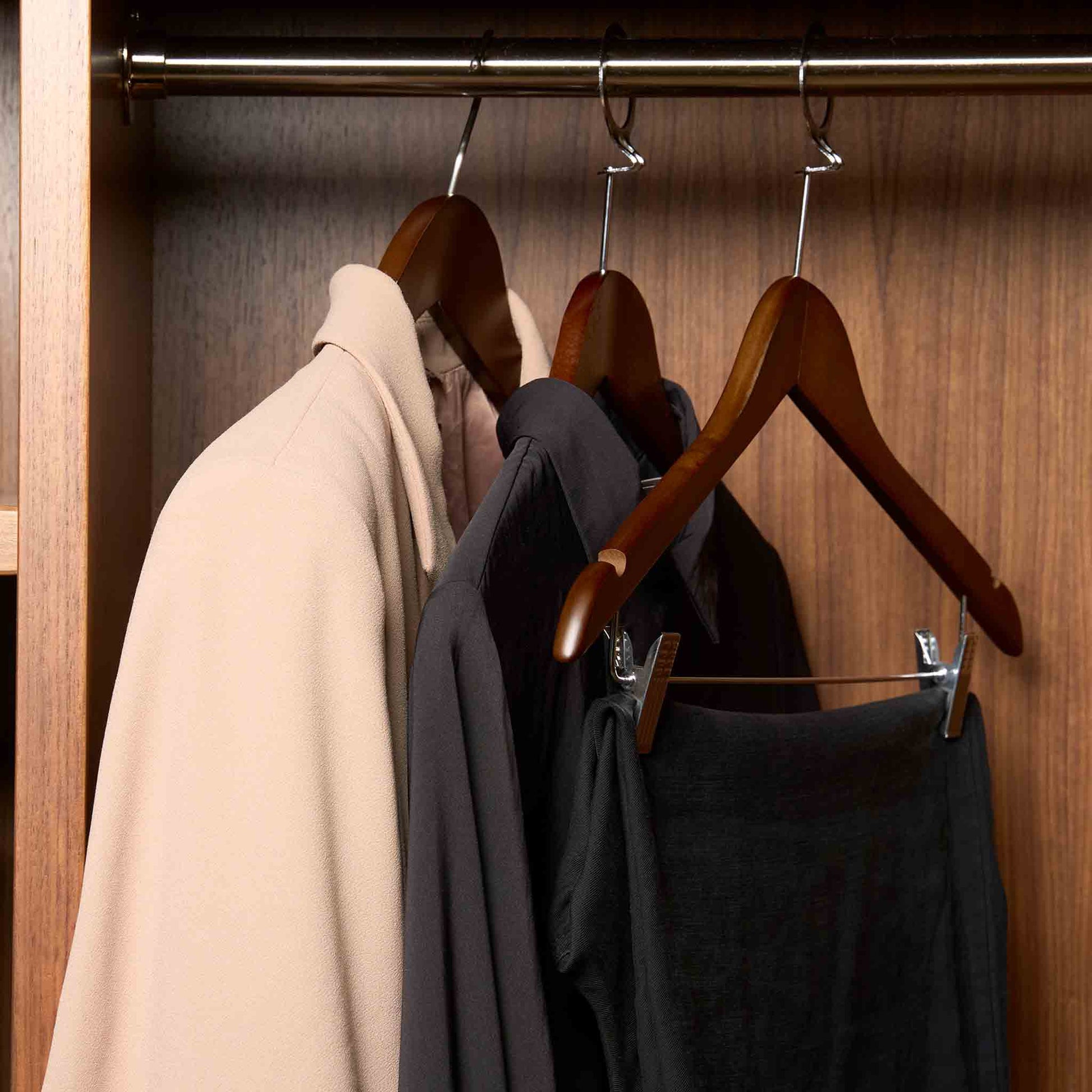 Corby Burlington dark wood security hangers with chrome clips and notches holding guest clothing on anti-theft rail in hotel wardrobe