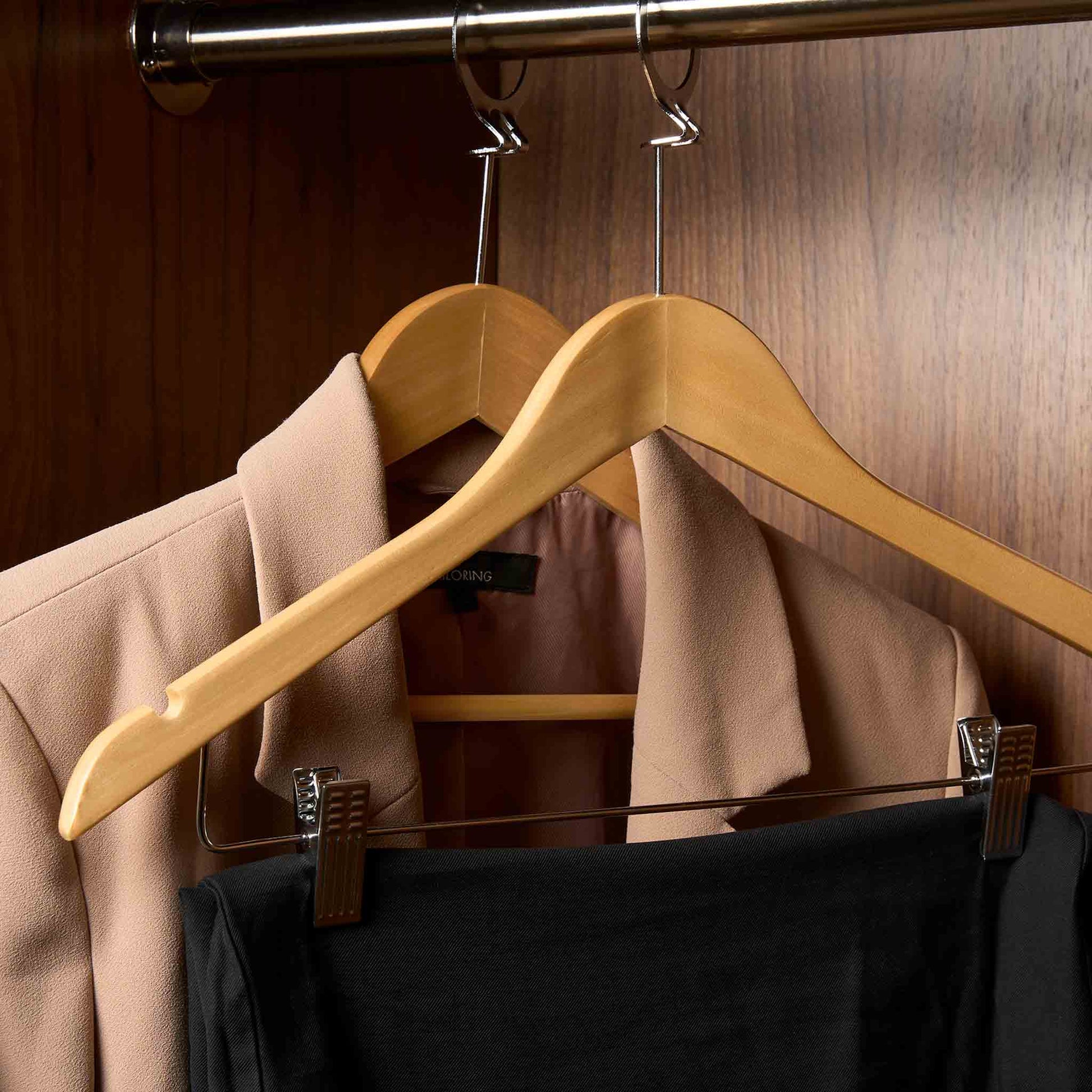 Corby Burlington light wood security hanger with chrome clips and garment hooks holding guest trousers in hotel wardrobe on anti-theft rail