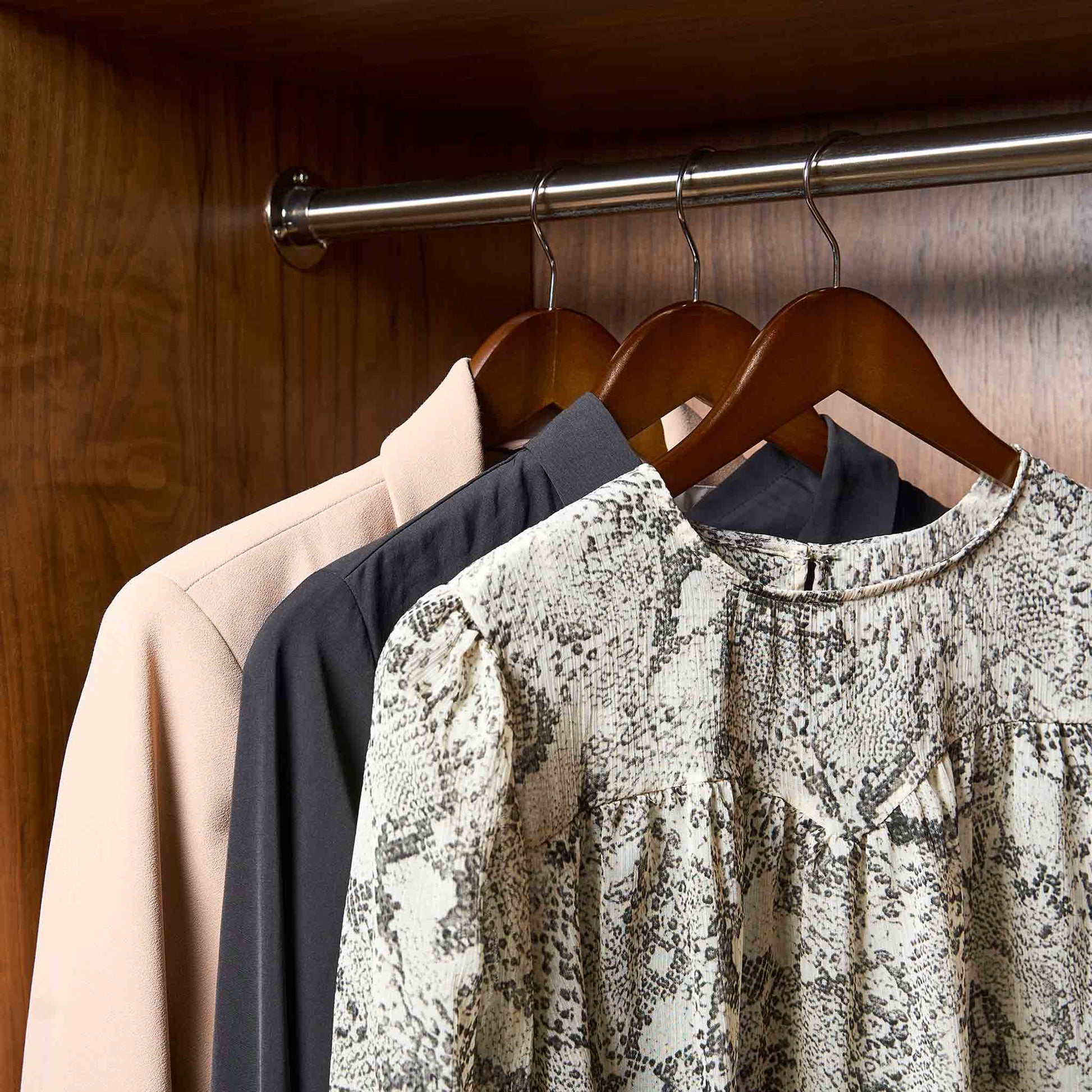 Corby Chelsea dark wood hangers with chrome hooks holding guest dress and jackets in hotel wardrobe