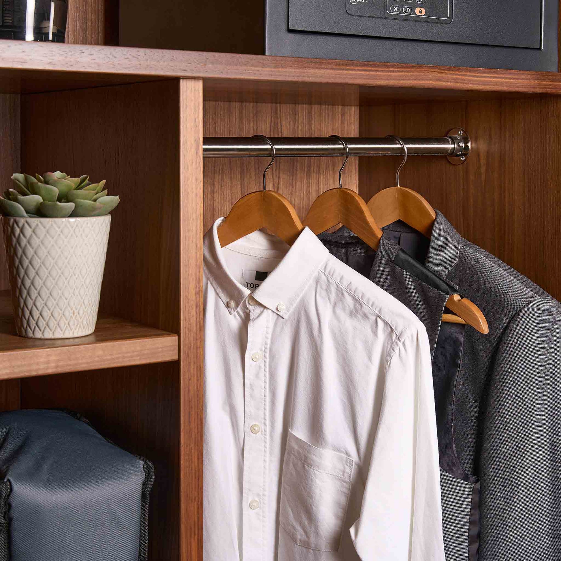 Corby Chelsea light wood guest hangers with chrome hooks holding white shirt and suit jacket in hotel wardrobe