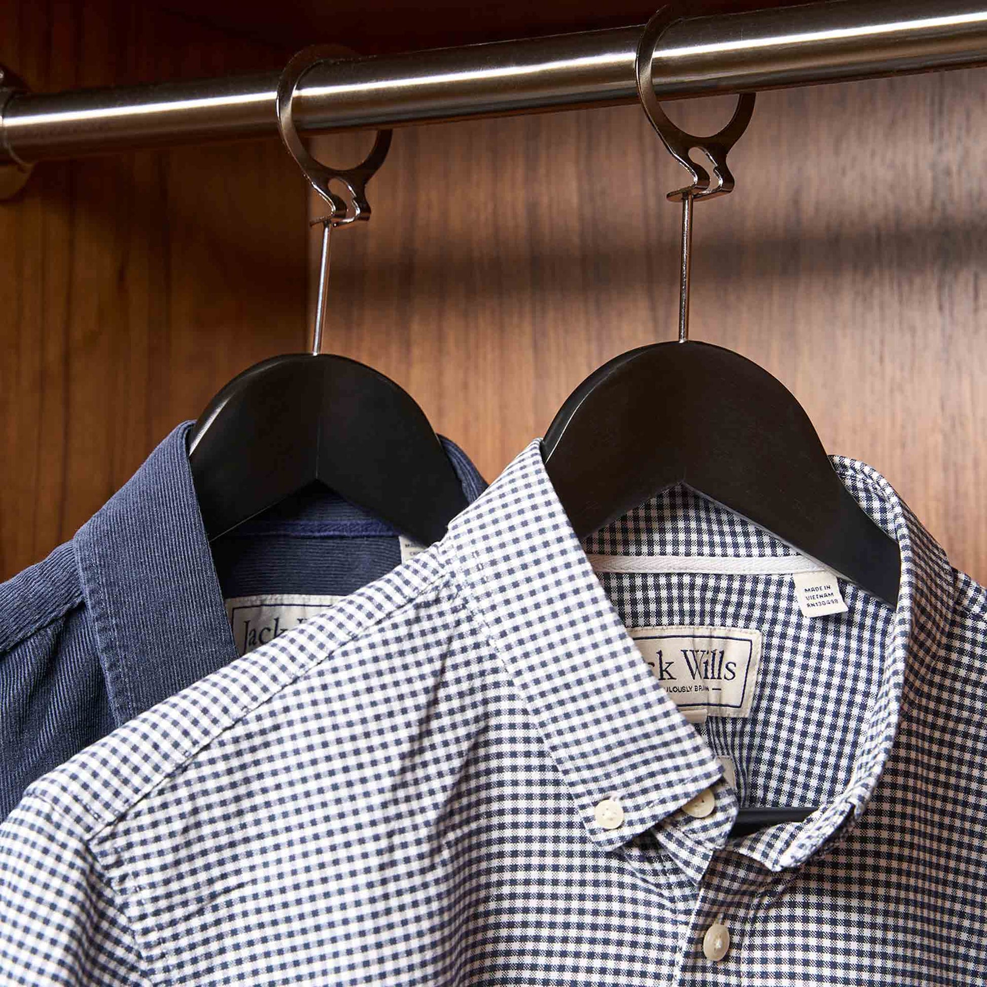 Matte black Corby Chelsea security hangers with chrome security pins in a hotel wardrobe, holding guest shirts on metal security rings