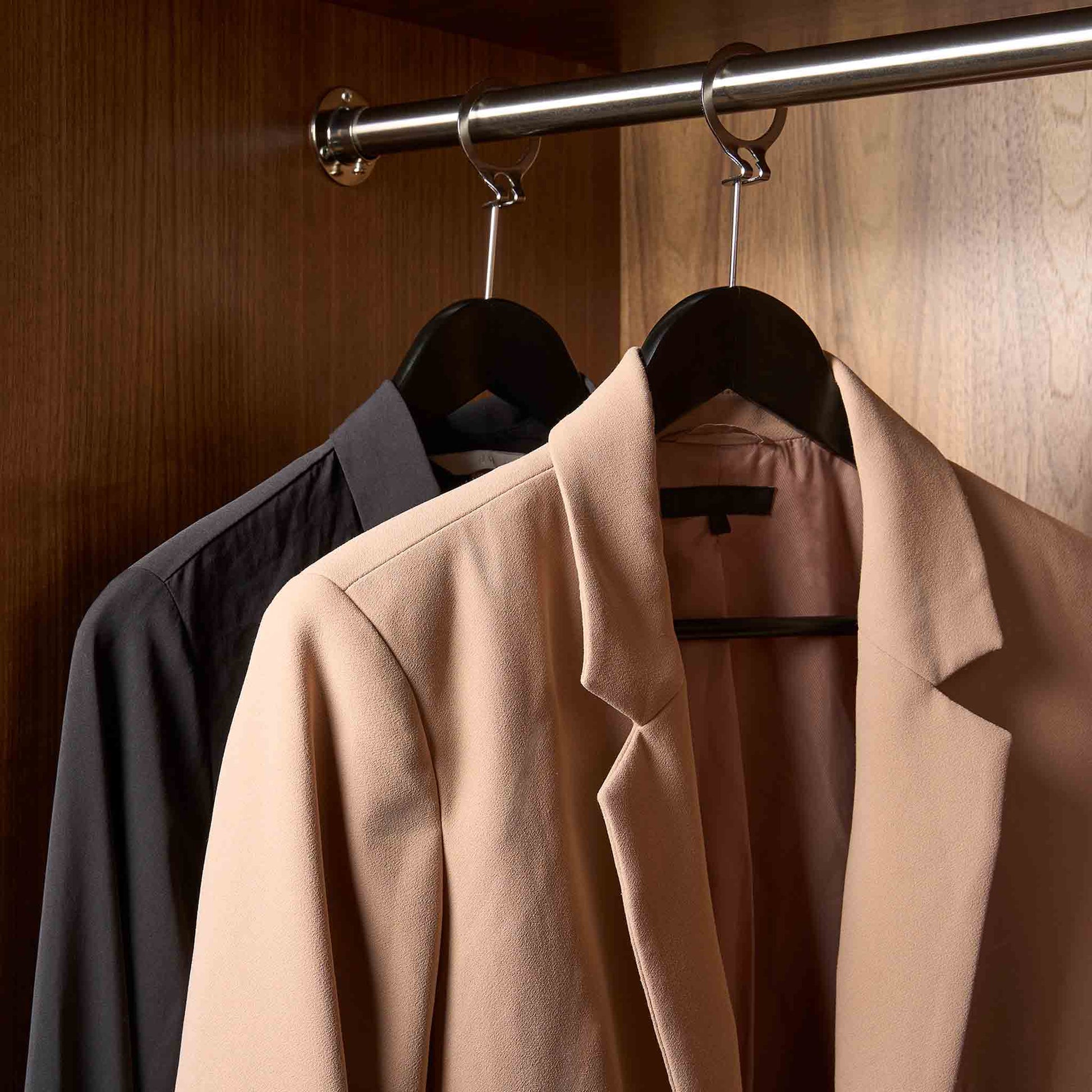 Matte black Corby Chelsea security hanger in hotel wardrobe, holding guest clothes and secured with anti-theft ring on clothes rail