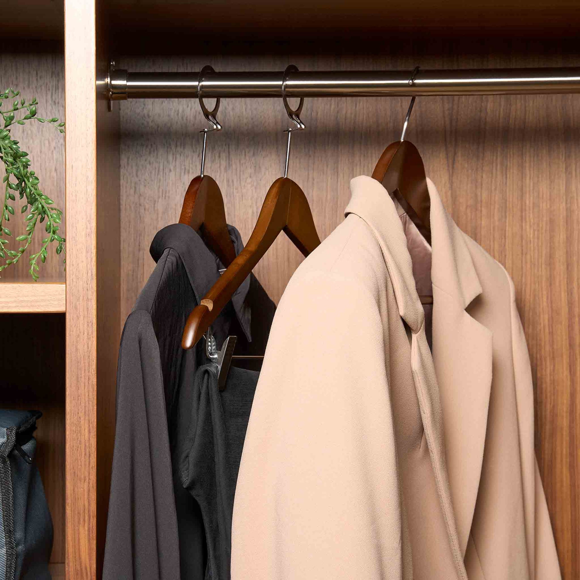 Corby Clifford dark wood hotel hangers with chrome hooks holding guest clothing in luxury wardrobe setting