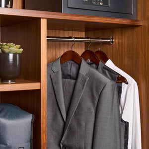 Corby Clifford dark wood suit hangers with chrome hooks holding guest clothing in hotel wardrobe with in-room safe