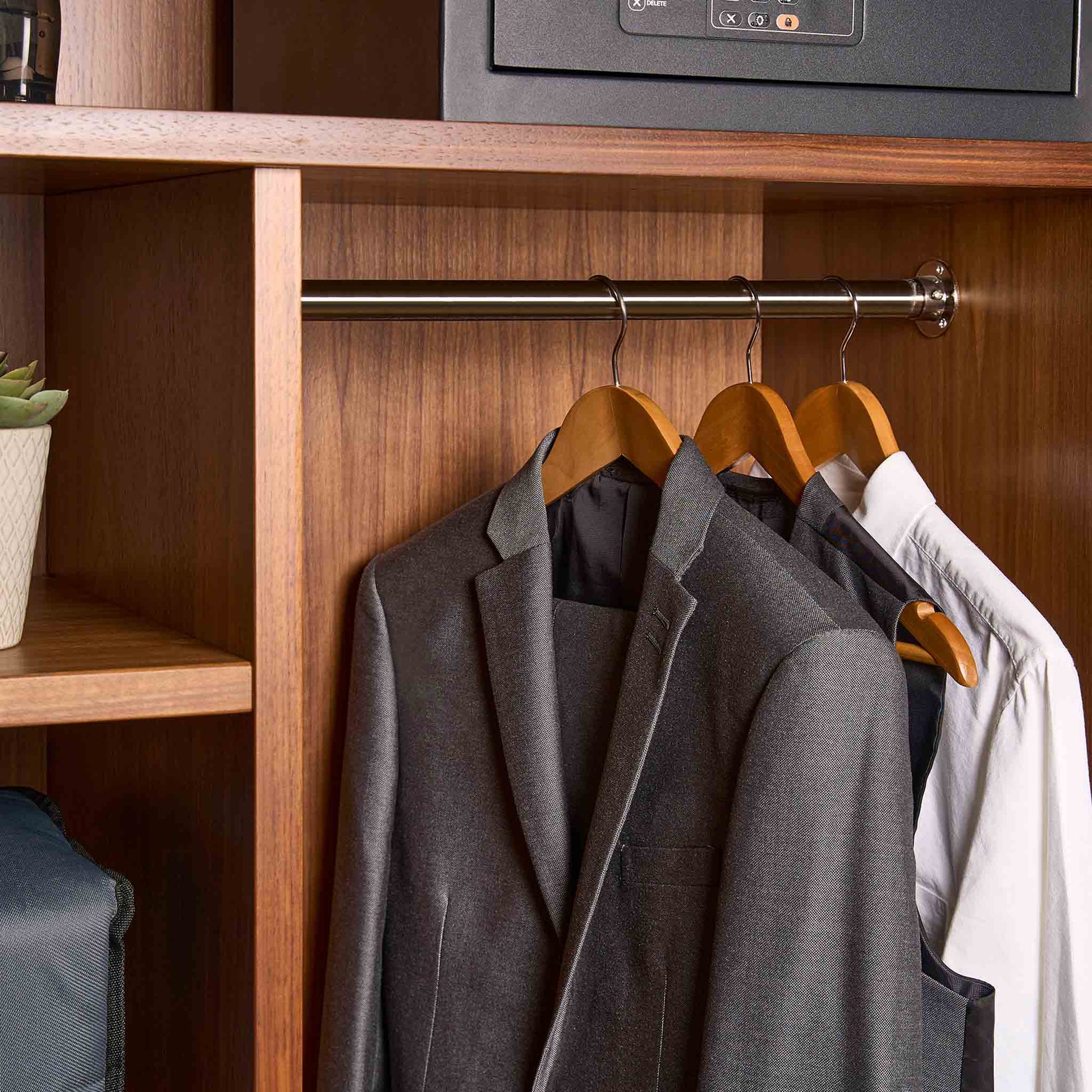 Corby Clifford light wood hotel hangers with chrome hooks displaying guest suit and shirt in fitted wardrobe with safe
