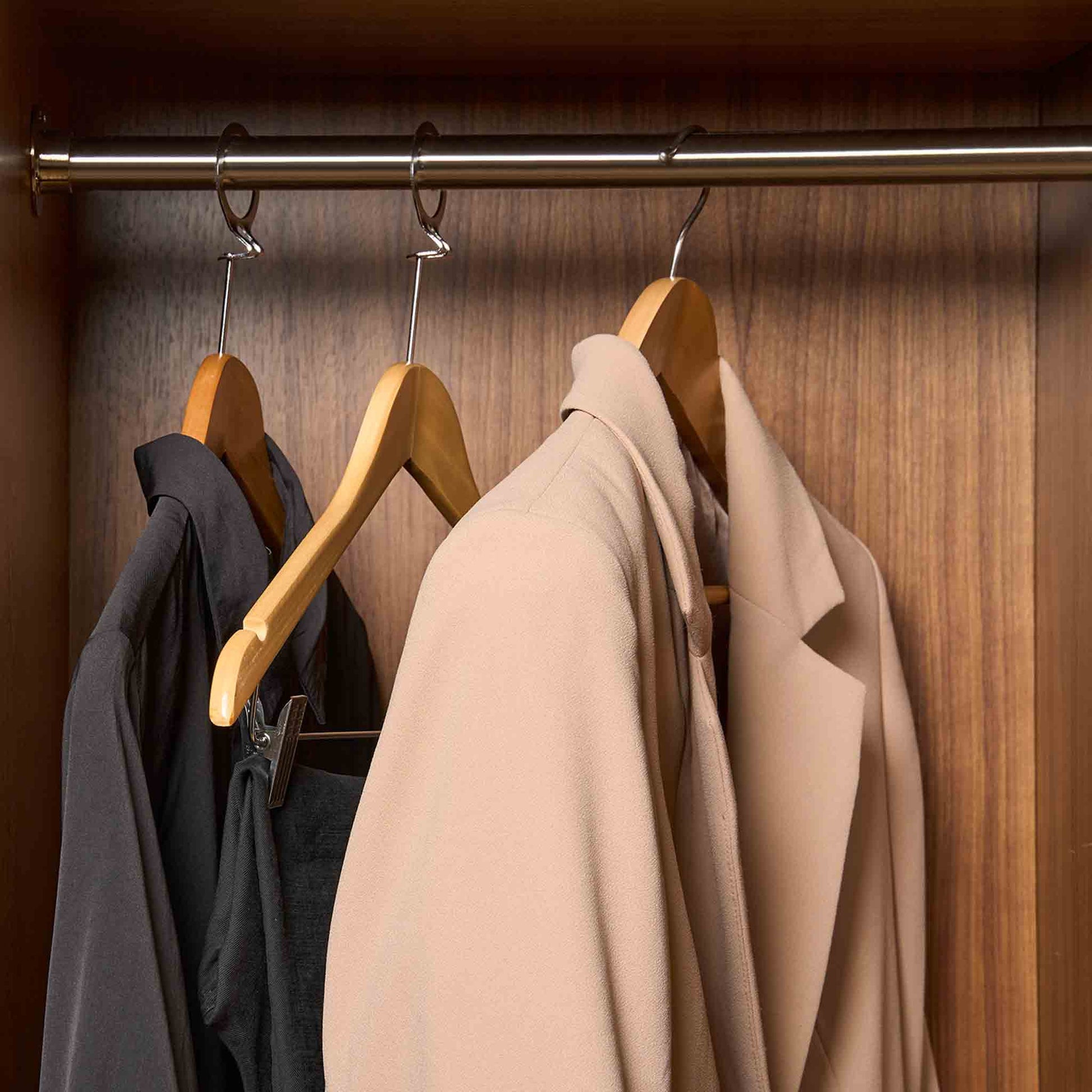 Corby Clifford light wood hotel hangers with chrome hooks holding guest jacket and clothing in luxury wardrobe setting