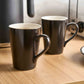 Pair of Corby Fenton black porcelain mugs on hotel room countertop with kettle and toaster, ideal for in-room hospitality service