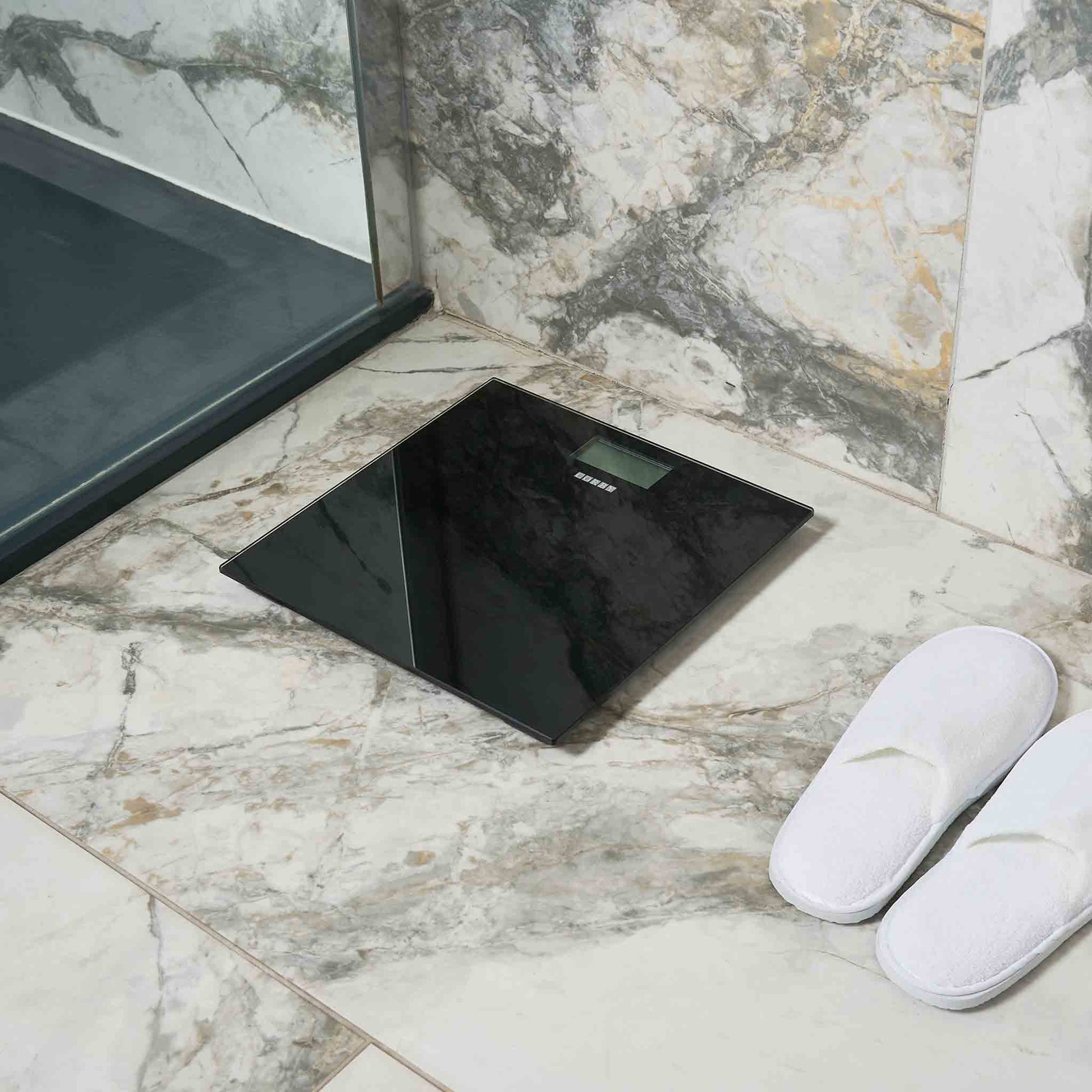 Corby Helmsley black digital bathroom scales placed in luxury hotel bathroom with marble tiles and slippers