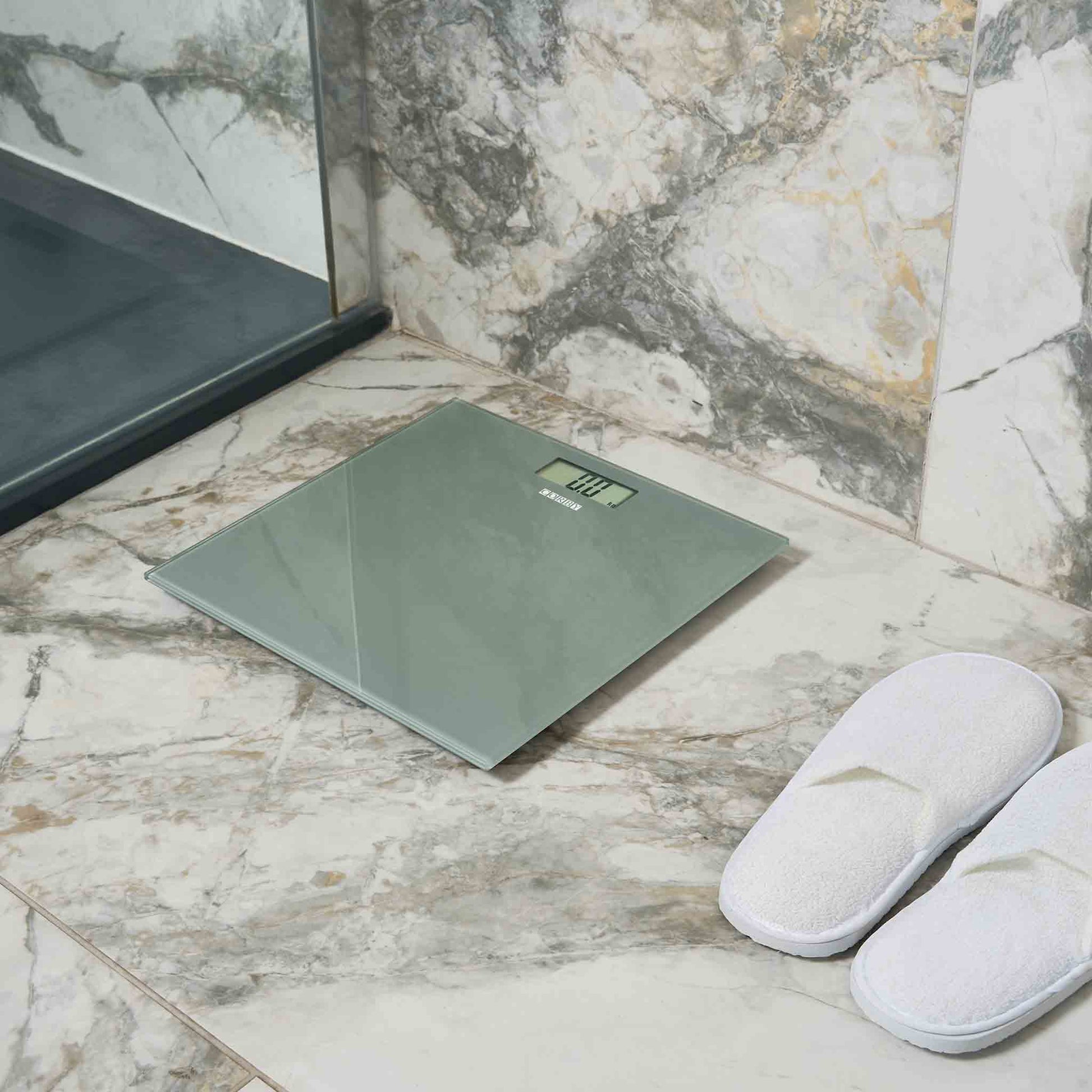 Corby Helmsley grey digital bathroom scales placed on marble floor in luxury hotel bathroom with white guest slippers
