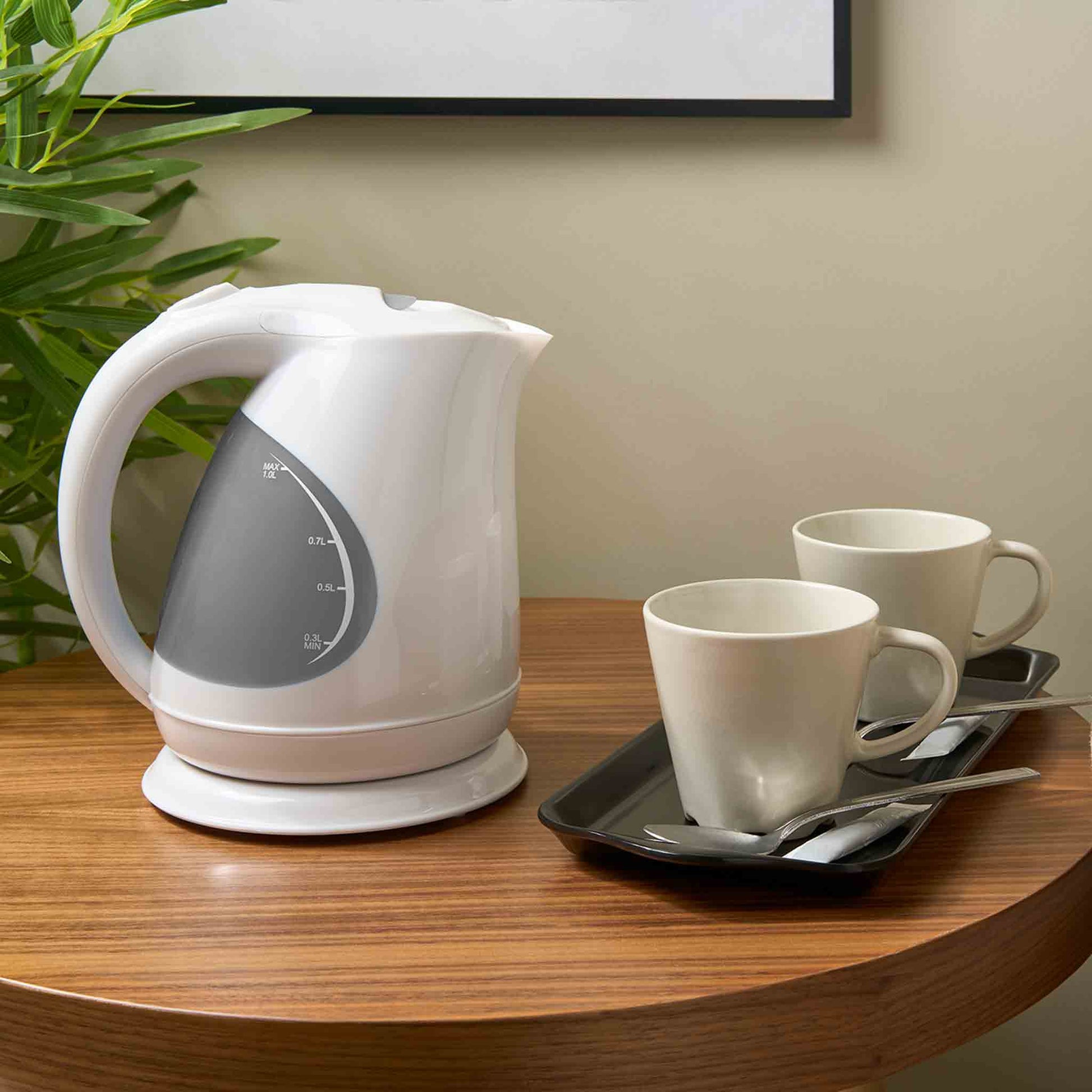 Corby Lancaster 1L white hotel kettle on wooden table with two mugs, spoons, and black hospitality tray in a guest room setting