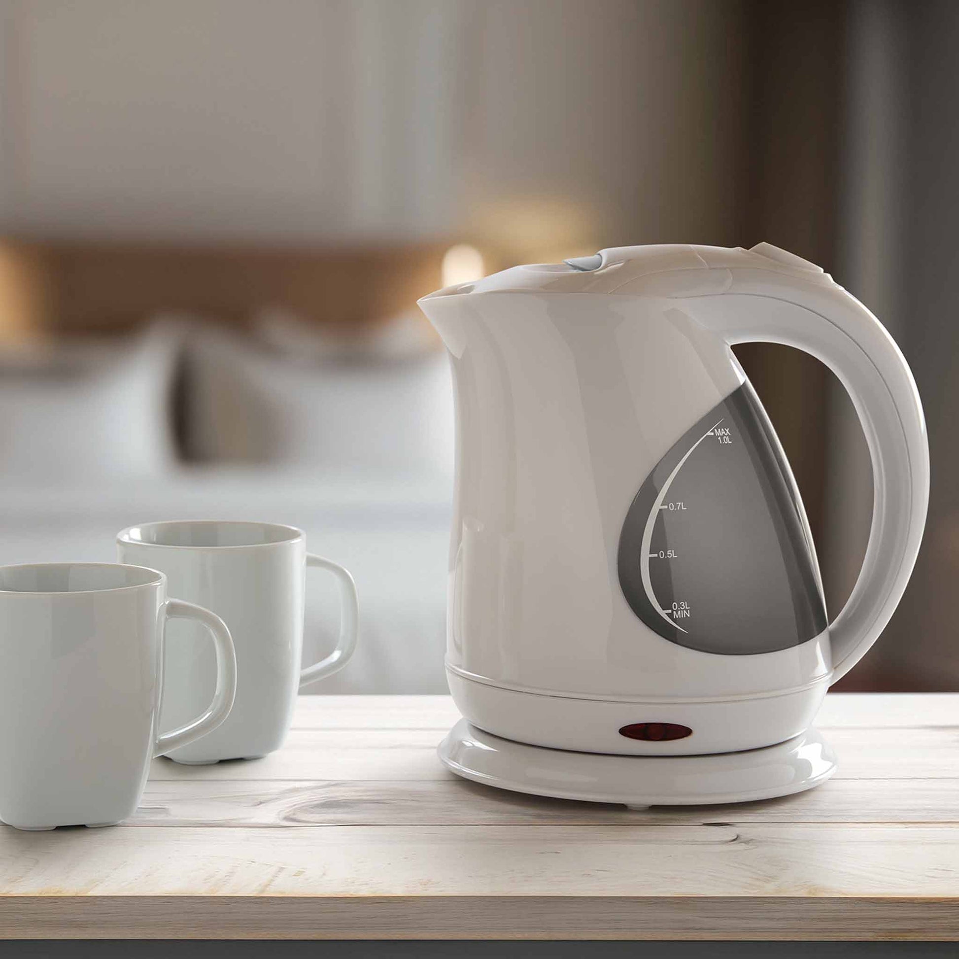 Corby Lancaster 1L white kettle with clear water gauge on a light wooden table in hotel room with two ceramic mugs