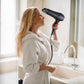 Hotel guest using hairdryer in hotel bathroom wearing a white bathrobe