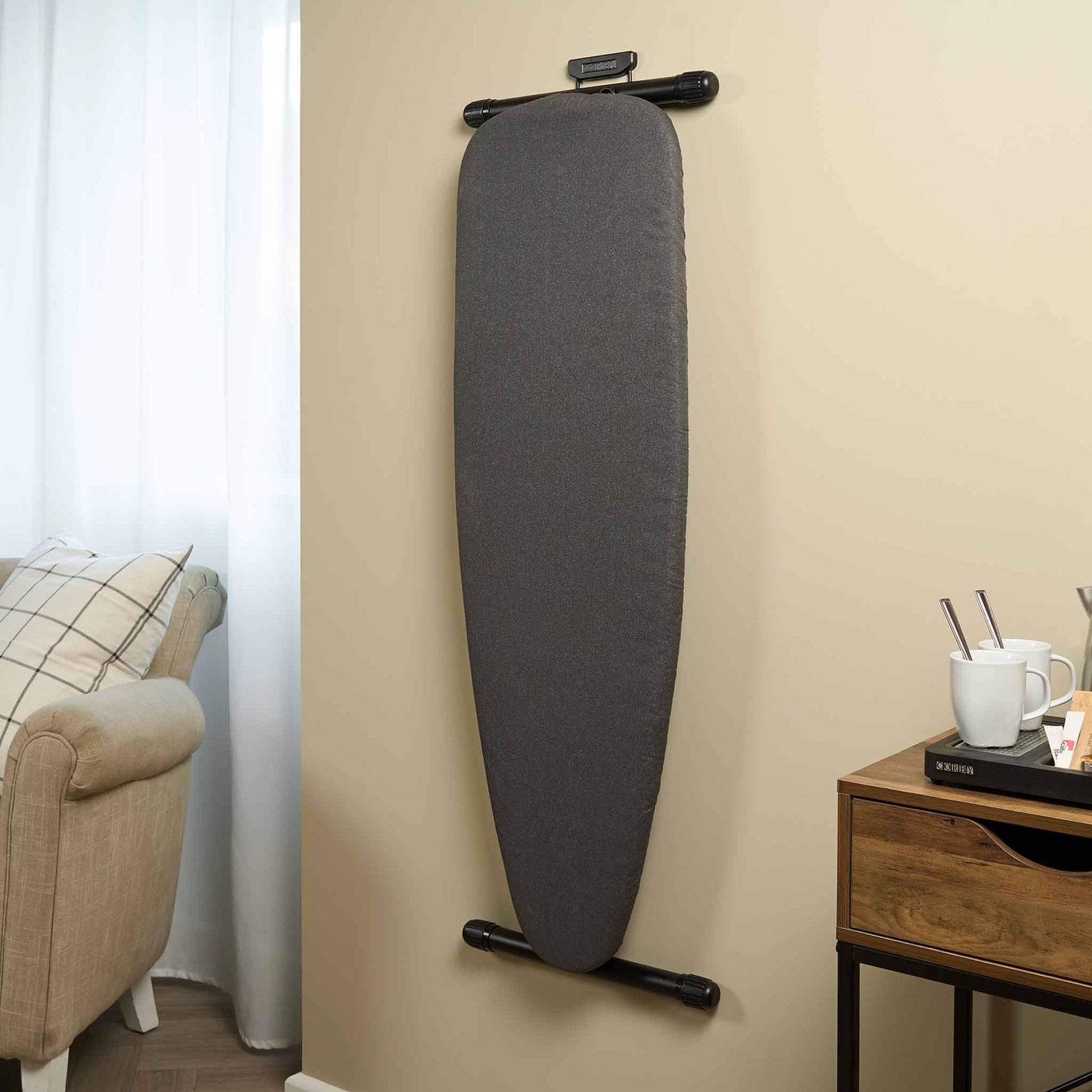 Corby Oxford dark grey ironing board wall-mounted in hotel room next to coffee tray and armchair