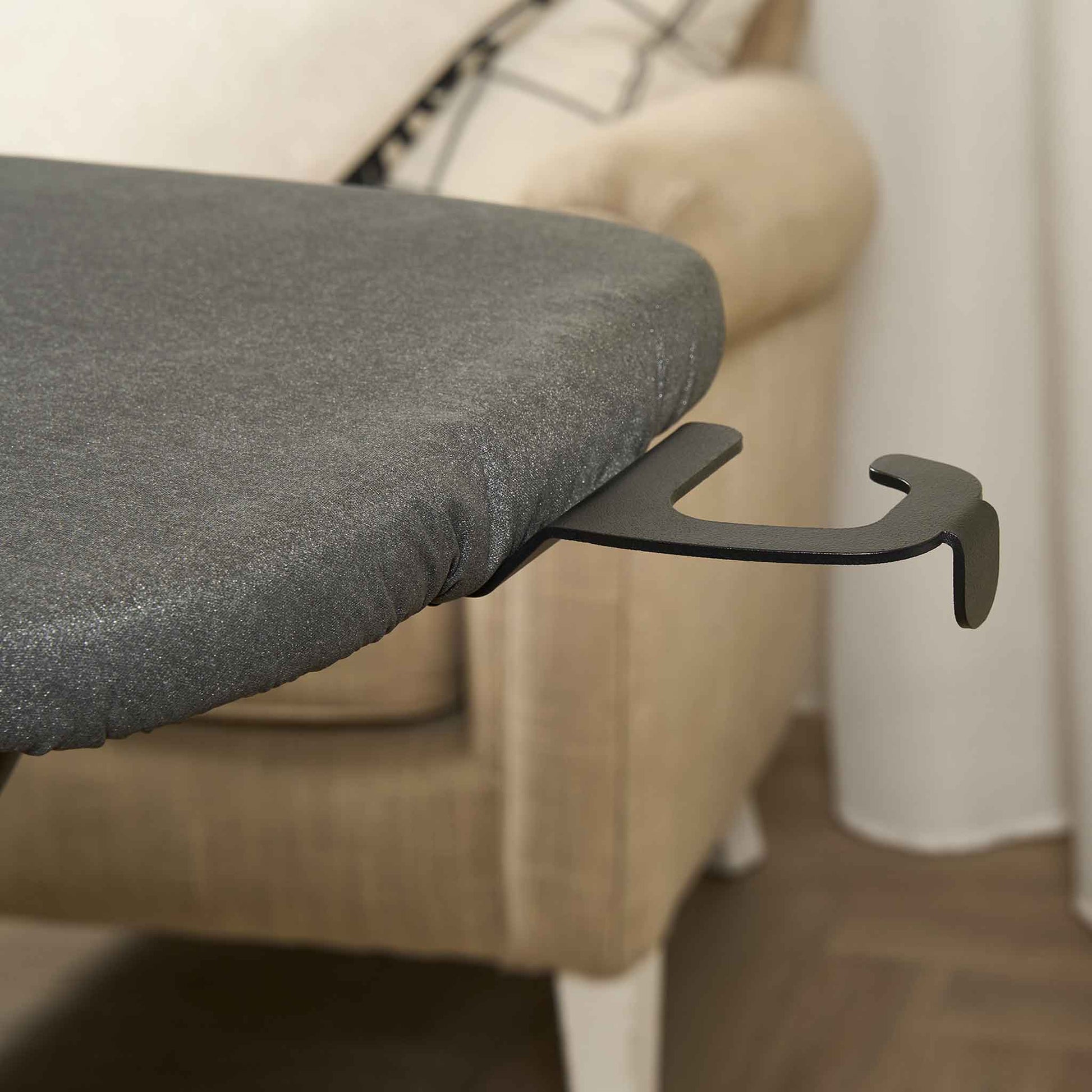 Corby Sherwood ironing board hanger attached to dark grey ironing board in hotel guest room with upholstered armchair