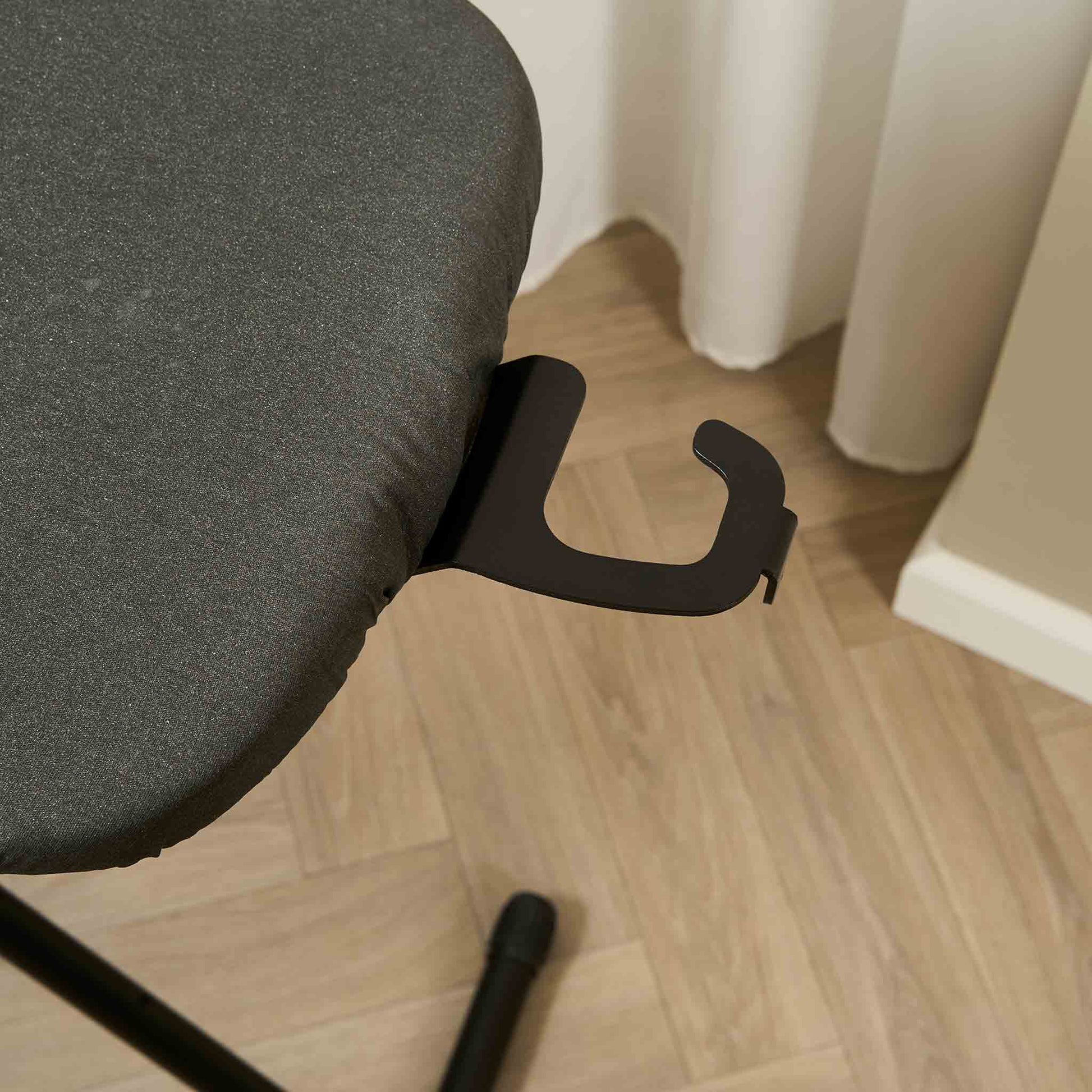 Close-up of Corby Sherwood ironing board hanger attached to dark grey ironing board in hotel room with wooden flooring