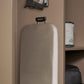 Corby Sherwood ironing board with light grey cover stored vertically in hotel wardrobe using compact black holder, iron mounted above