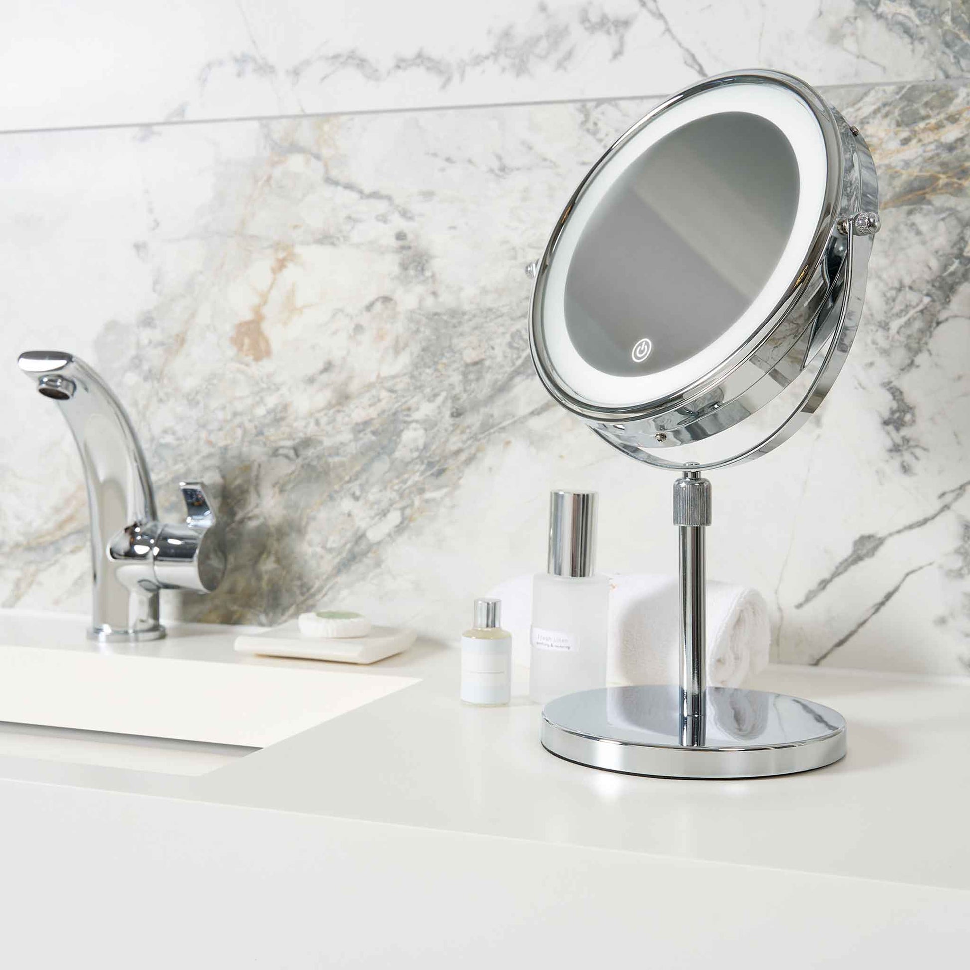 Corby Winchester chrome LED vanity mirror with touch sensor on hotel bathroom counter beside toiletries and chrome tap