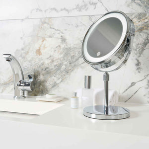Corby Winchester chrome LED vanity mirror with touch sensor on hotel bathroom counter beside toiletries and chrome tap