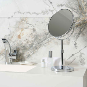 Corby Winchester chrome vanity mirror with magnification on hotel bathroom countertop beside chrome tap and toiletries