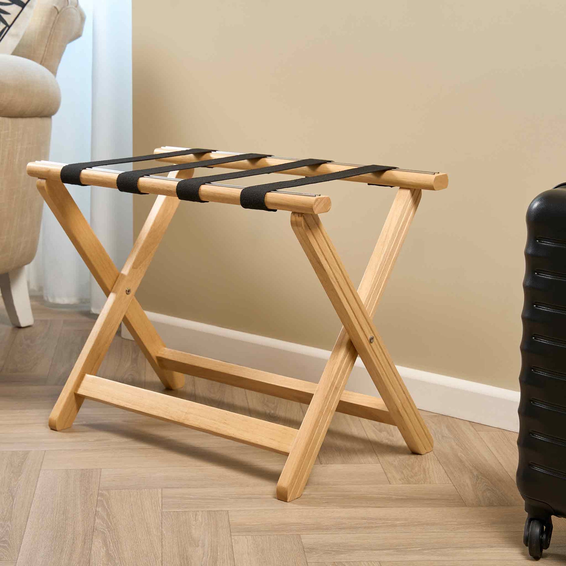 Corby York light wood suitcase stand with foldable X-frame and black nylon straps in modern hotel guest room