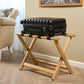 Corby York light wood hotel luggage rack with black fabric straps, holding hard-shell suitcase in guest room setting with neutral décor