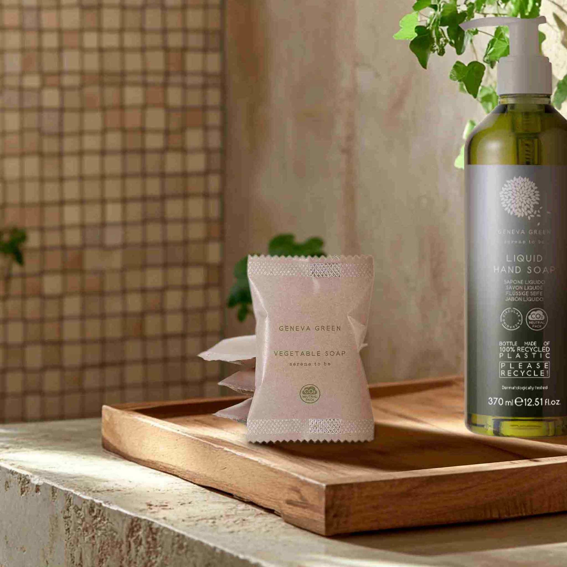 Bottle of liquid hand soap and a bar of soap on a wooden tray with a neutral background