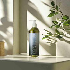 Geneva Green 370ml hair and body wash in recycled plastic pump bottle, placed on hotel bathroom shelf with natural light and greenery