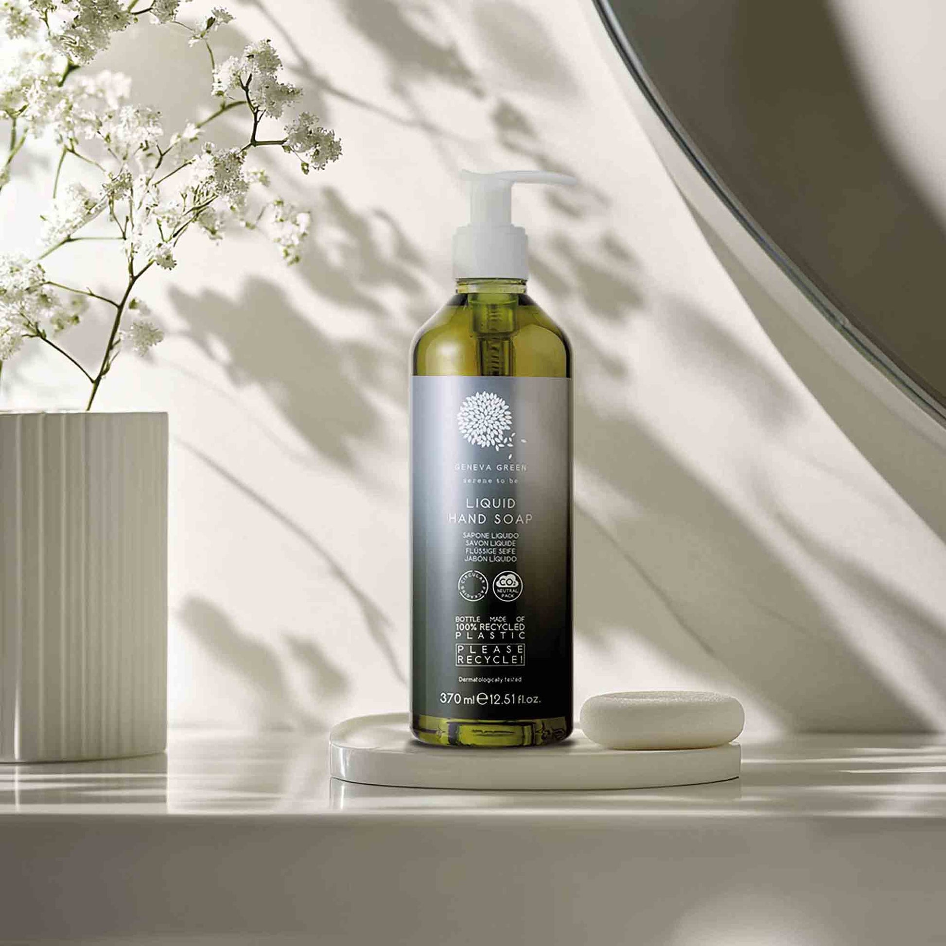 Geneva Green 370ml liquid hand soap in recycled PET bottle displayed in modern bathroom with floral decor and natural light