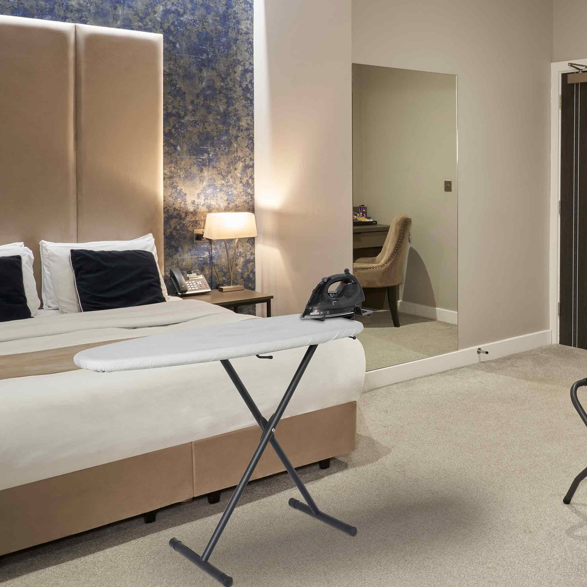 Corby Oxford Premium Ironing Centre with 2000W steam iron set up in modern hotel bedroom with king-size bed and desk area