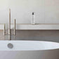 Bottle of Prija body lotion on a bathroom shelf with a bathtub in the foreground