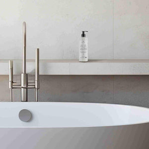 Bottle of Prija body lotion on a bathroom shelf with a bathtub in the foreground