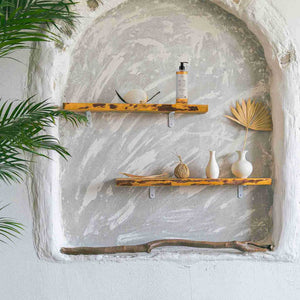 Wooden shelves with Prija shampoo in pump dispenser and decorative items against a textured wall.