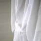 A close-up of a white terry towelling bathrobe with a matching belt, showing the soft texture of the fabric.